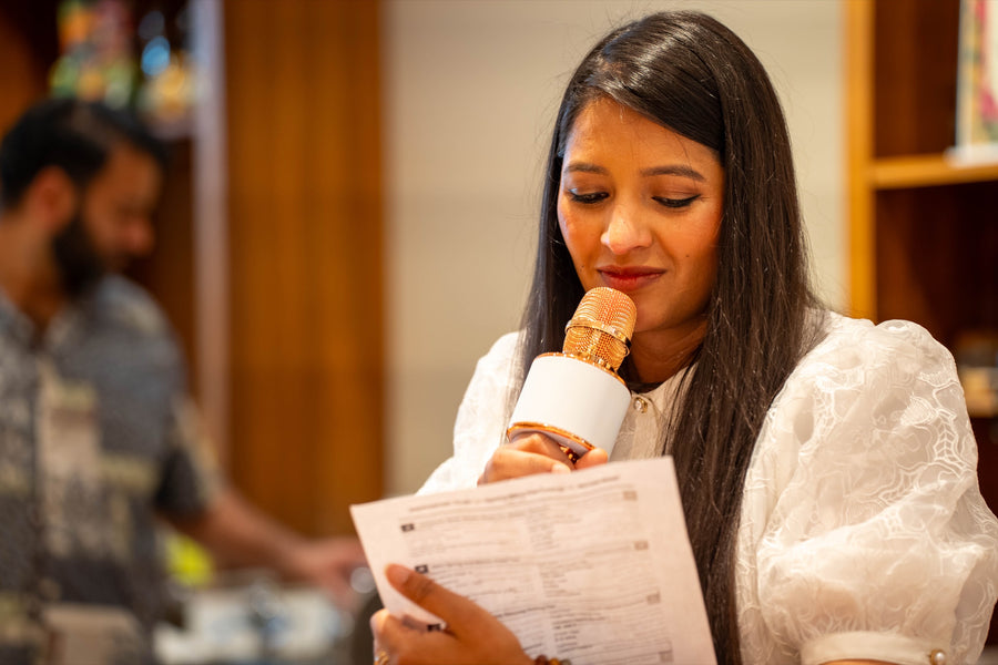 Rini reading from a card at the shop in spring 2026